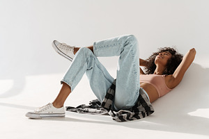 Young african woman wearing jeans smiling while lying on floor