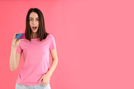 Attractive woman in t-shirt holds card on pink background, a Person Photo by AtlasStudio PRO