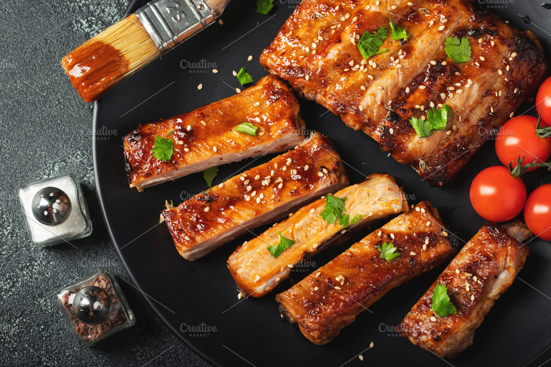 Hot grilled spare ribs from a summer BBQ served on a plate with sauce. Top view, a Food & Drink Photo by Budarinphoto