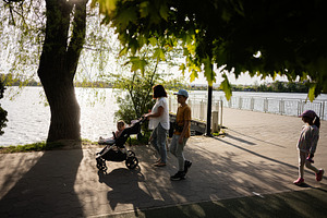 Family walking along a scenic river promenade during a sunny day, a Person Photo by AS photostudio