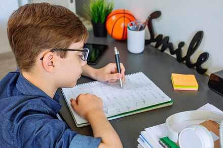 Left handed teenager doing homework in his bedroom, a School & Education Photo by davidpereiras