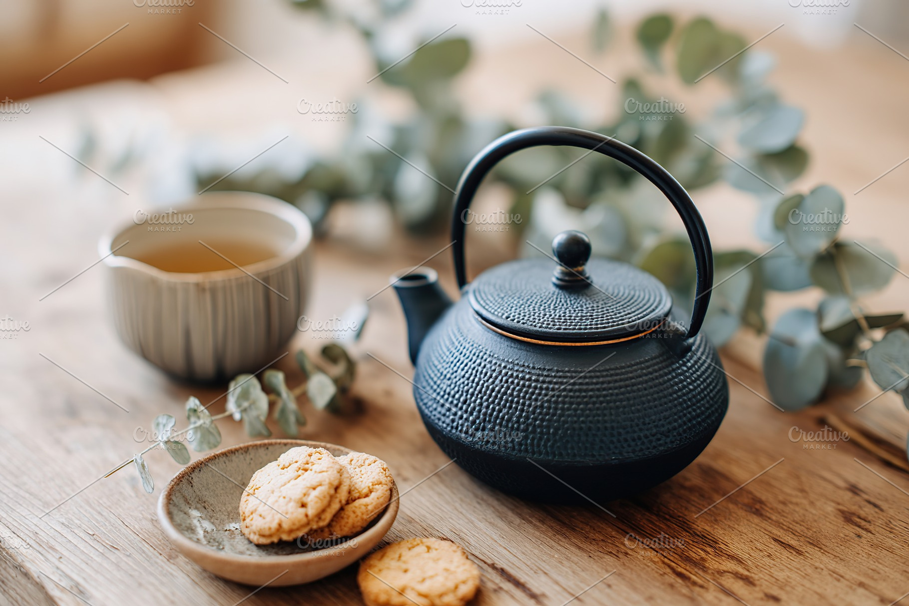 Cozy kitchen with black teapot, cookies, and herbal tea on a wooden table, a Food & Drink Photo by AlyaAnd