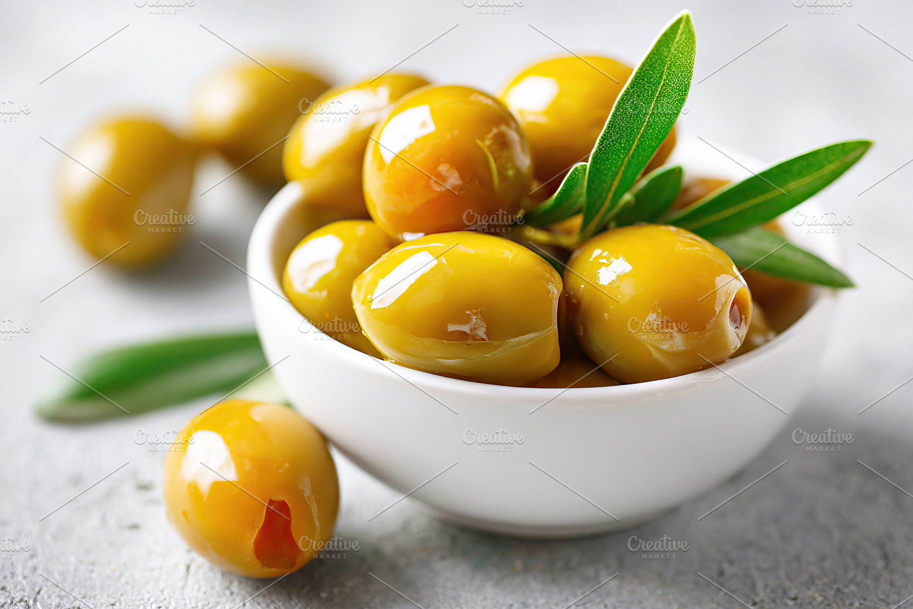 Glossy marinated olives served in a white bowl on a gray surface, a Food & Drink Photo by AlyaAnd