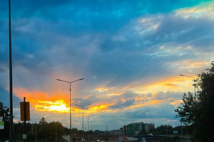 Scenic urban road at sunset with dramatic sky and illuminated street lights, a Photo by AS photostudio