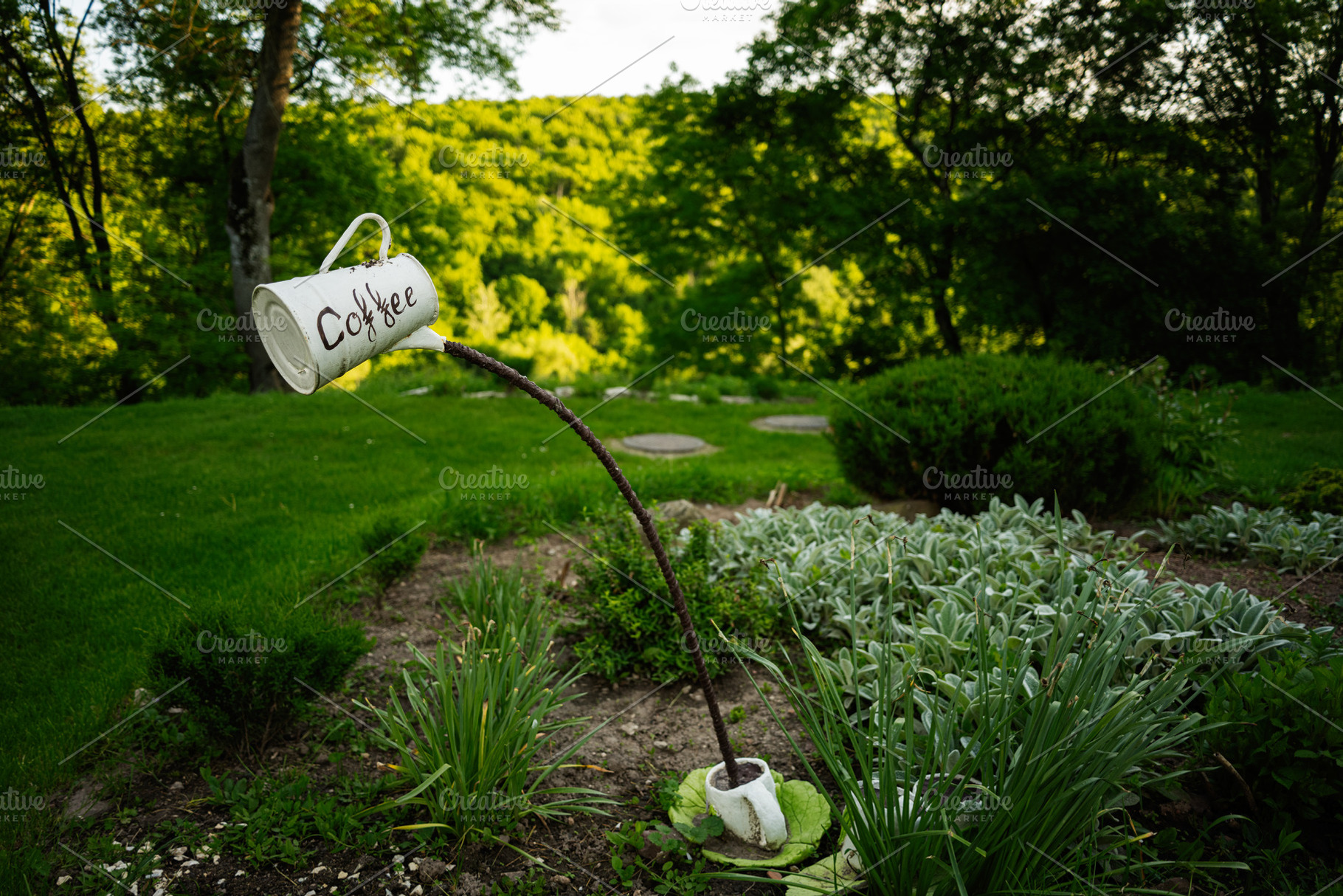 Creative garden decoration with a coffee cup sculpture and lush greenery, a Photo by AS photostudio