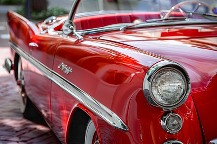 A striking red convertible is parked, a Photo by Tanuart