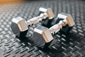 Shiny metal dumbbells on textured surface, a Sports & Recreation Photo by AlyaAnd