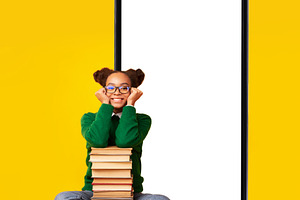 Black teen girl sitting near smartphone and books, yellow background, a Photo by Prostock-Studio