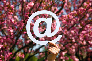 A hand holds a white at symbol in front of a blooming cherry blo, a Nature Photo by Ales Munt