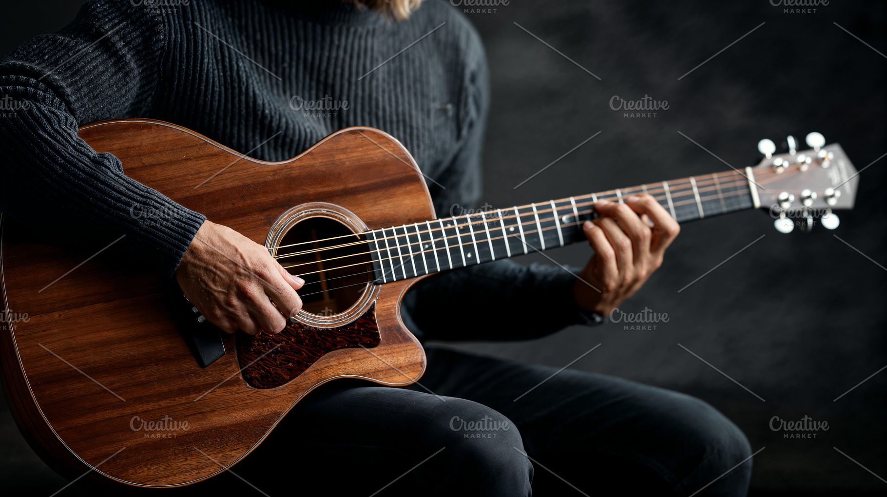 Expert musician plays acoustic guitar in dim studio setting, a Photo by OSORIOartist