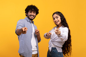And what's about you. Excited indian couple pointing index fingers at camera, p, a Photo by Prostock-Studio