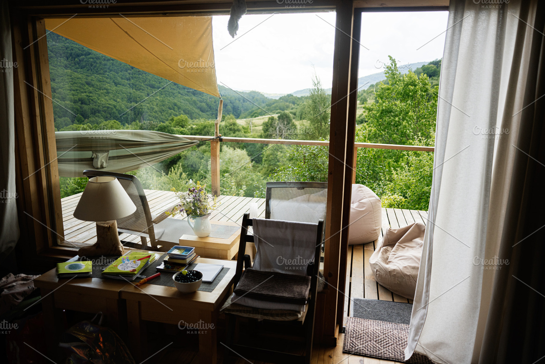 Rustic interior with deck view towards lush green landscape and beanbag chairs, a Photo by AS photostudio