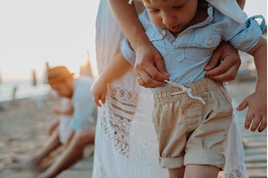 Mother adjusting little boy clothes, a Person Photo by HalfPoint