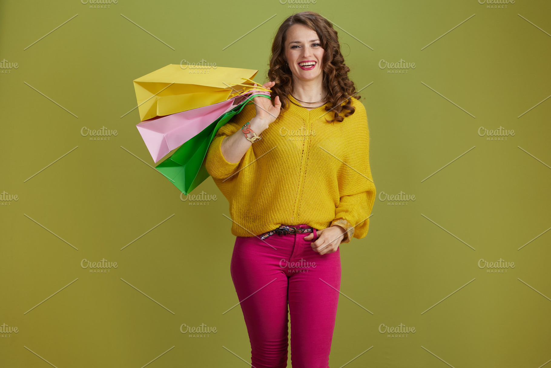 smiling trendy woman in yellow sweater against green background, a Photo by Alliance Images