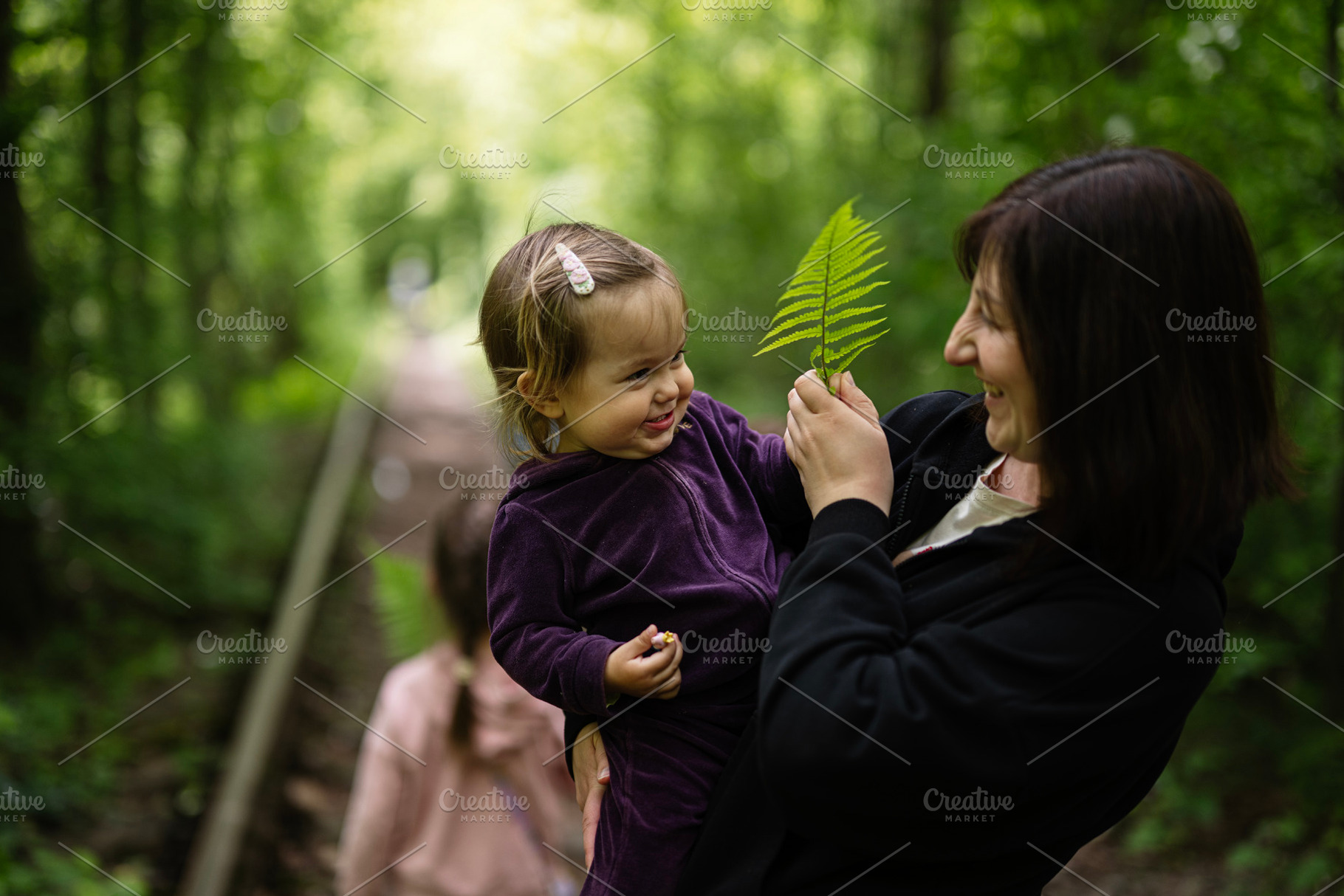 Mother and child enjoying nature while exploring greenery in a forest, a Photo by AS photostudio
