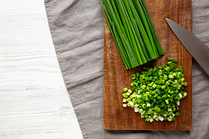 Organic Cut Green Onion Scallions on a Wooden Board, top view. C, a Food & Drink Photo by LiudmylaChuhunova