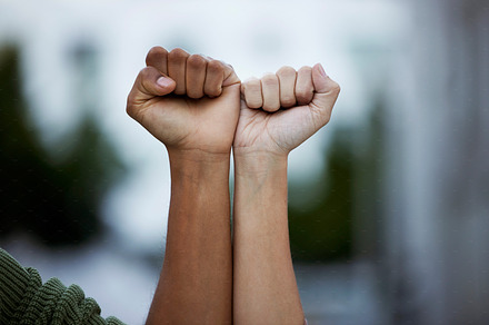 Fist, protest and power by people in solidarity for justice, human rights and democracy on blurred background. Hands, diversity and men united for activism, change and transformation or community, a Photo by Peopleimages.com