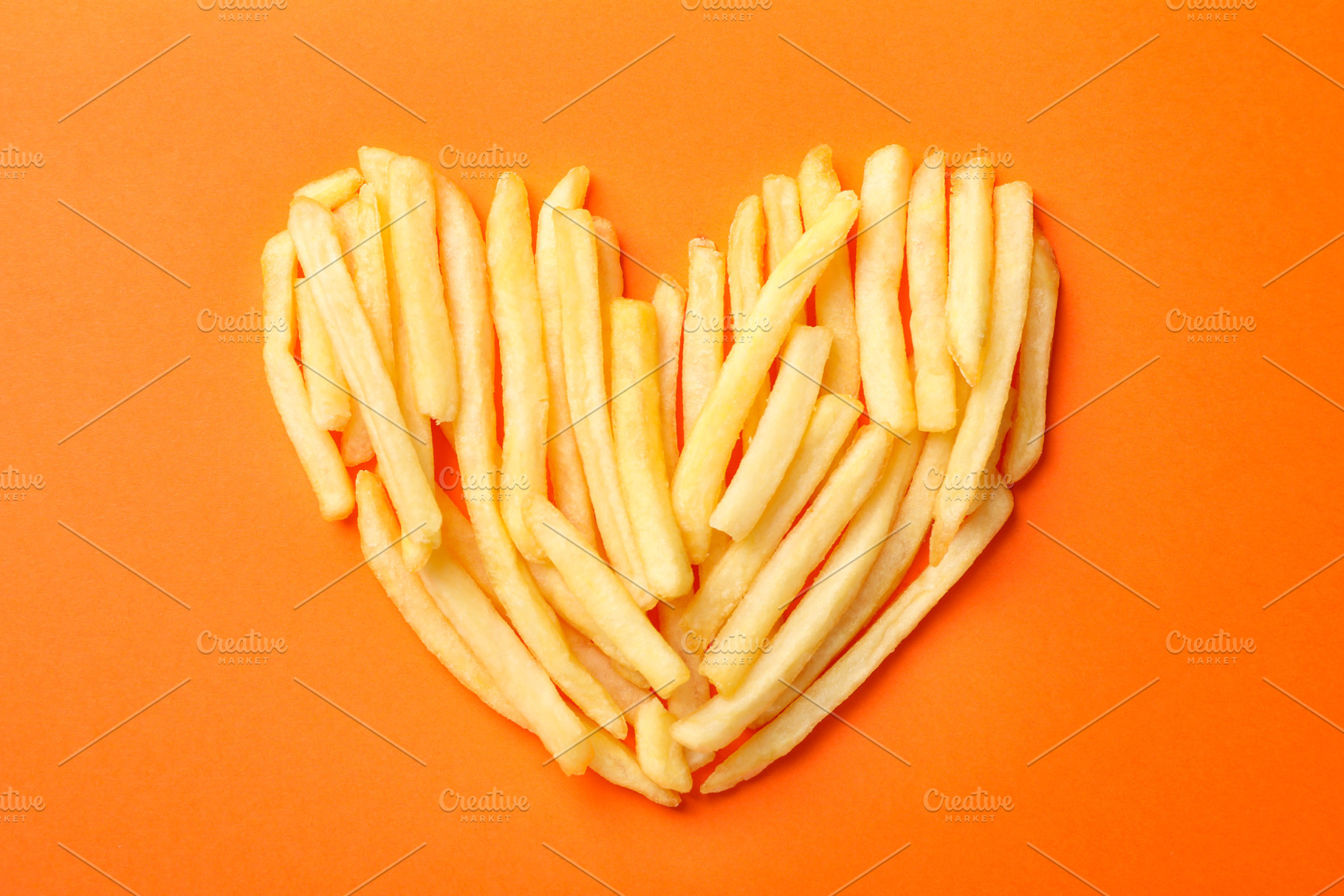 Handmade heart with tasty french fries on orange background, top, a Food & Drink Photo by AtlasStudio PRO