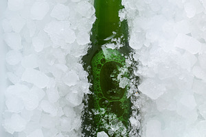 Green beer bottle buried in a pile of ice cubes, a Food & Drink Photo by Davizro's Market