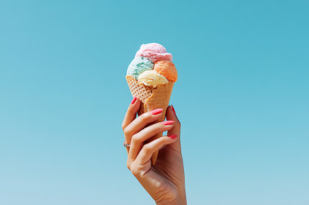 Hand holding a melting ice cream cone under a bright blue sky in summer, a Food & Drink Photo by AlyaAnd