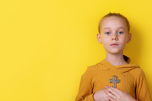 Portrait of a young girl in a mustard sweater holding a cross pe, a Person Photo by Ales Munt