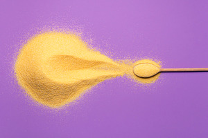 Corn flour pile and a spoon on purpl