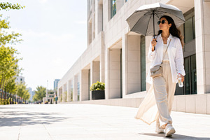Woman walking under umbrella on sunn, a Photo by Dvoevnore photos