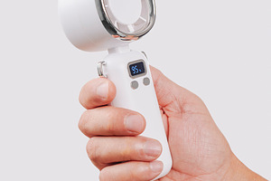 close-up of a man cooling himself with a white fan, a Photo by Nito