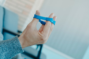 man exercising his fingers with an elastic band, a Photo by Nito