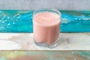 Fresh pink smoothie in clear glass on colorful wood background. Healthy refresh, a Food & Drink Photo by Eugene_Photo