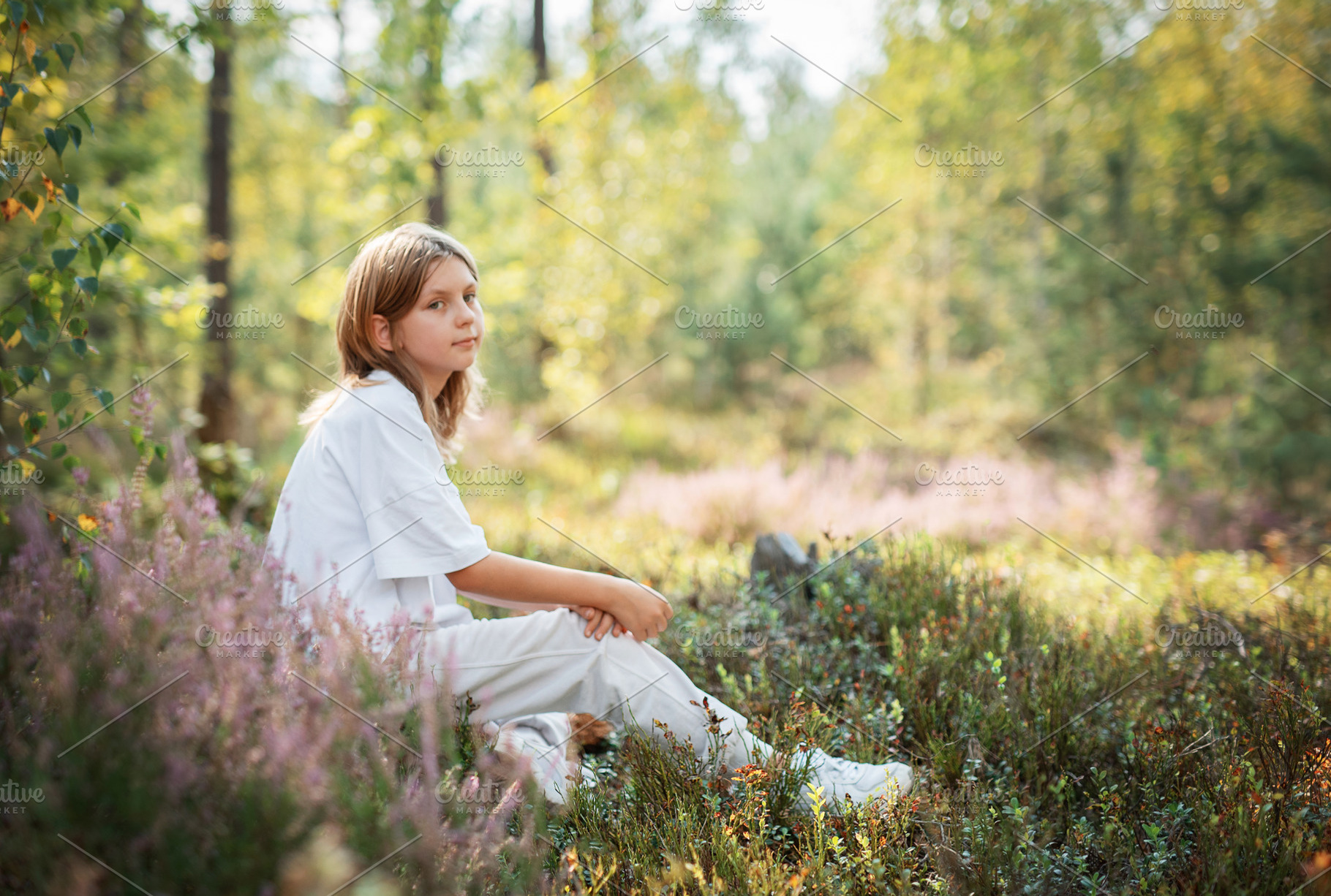 A young child sitting quietly in a serene forest, surrounded by, a Person Photo by Olena Rudo