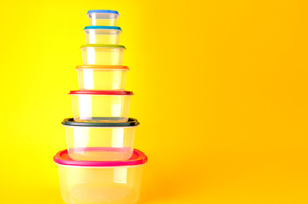 Stack of transparent plastic food containers with colorful lids,