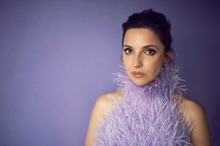 portrait woman in an evening purple dress with feathers stands in the backgroun, a Person Photo by SaulichPhoto