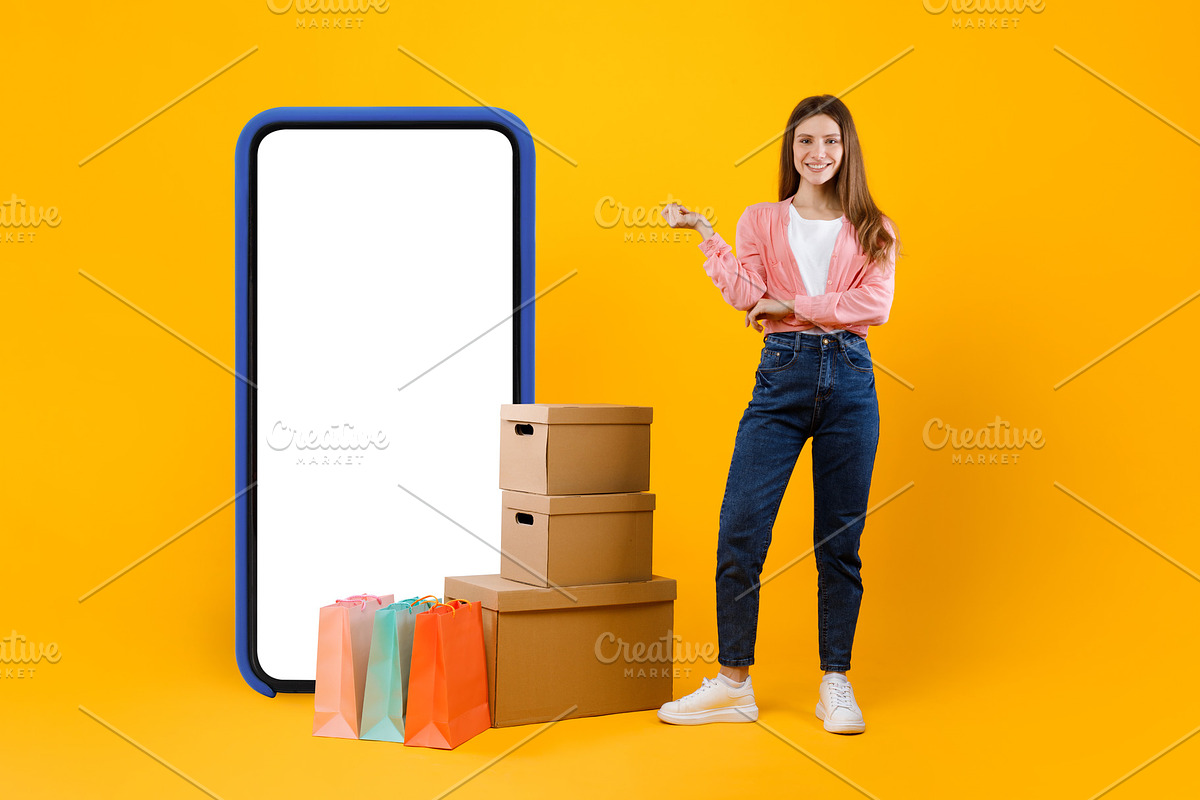 Woman Standing Near Big Phone And Cardboard Boxes, Yellow Background, a Photo by Prostock-Studio (Photo 2 of 2)
