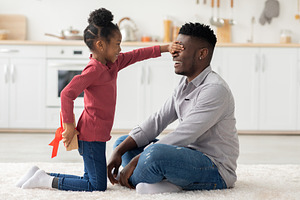 Cute little girl making birthday surprise for her dad, a Photo by Prostock-Studio
