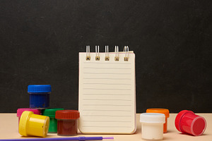 An open white spiral notebook surrounded by colorful paint cans, a School & Education Photo by ndanko