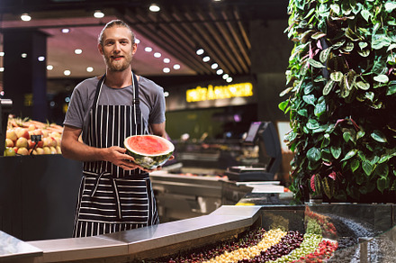 Young salesman in striped apron behi stock photo containing berries and person