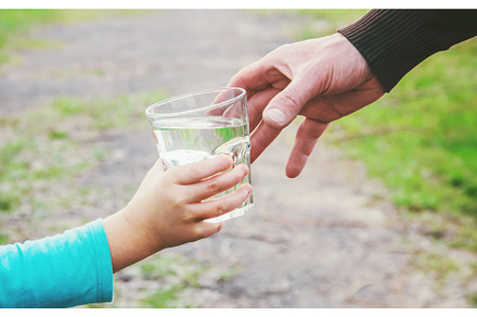 The father gives the child a glass, a Food & Drink Photo by yanadjana