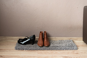 Brown ankle boots and black shoes on rug in entryway, an Industrial Photo by MDBildes