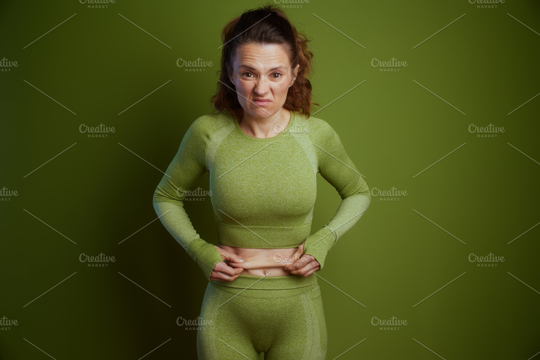 Frustrated woman pinching her stomach fat, a Person Photo by Alliance Images