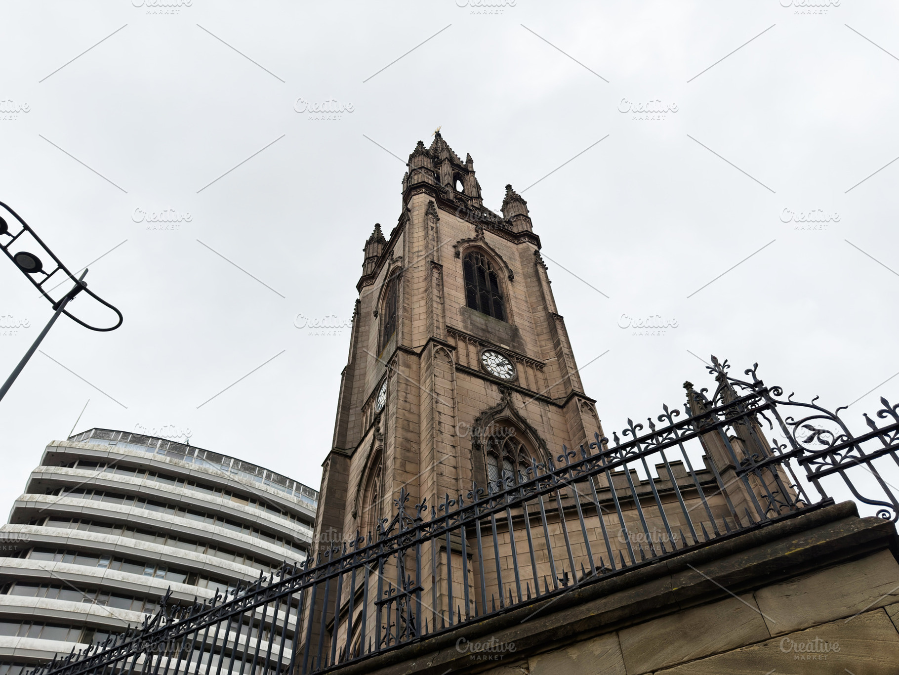 Historic Gothic church clock tower with ornate iron fence in Liv, a Photo by AS photostudio