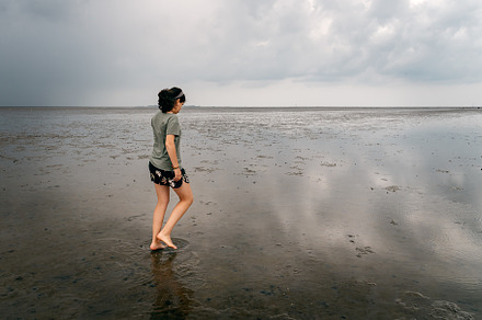 Young woman walking alone in a calm and tranquil beach at low tide, a Person Photo by Architect´s eye