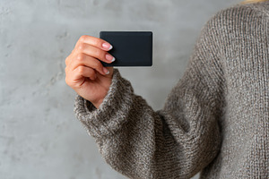 A woman with light skin holding a minimalist black card against a neutral backd, a Business Photo by ImageMir
