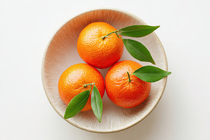 Three fresh mandarins arranged in a deep white bowl with green leaves on a neut, a Food & Drink Photo by AlyaAnd