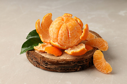 Board with mandarin and leaves on light textured background, a Food & Drink Photo by AtlasStudio PRO