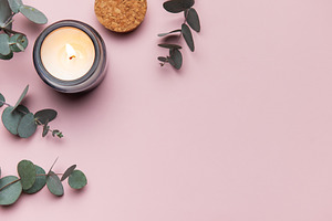 Burning aromatic candle with eucalyptus branches on pink backgro, a Business Photo by Olena Rudo