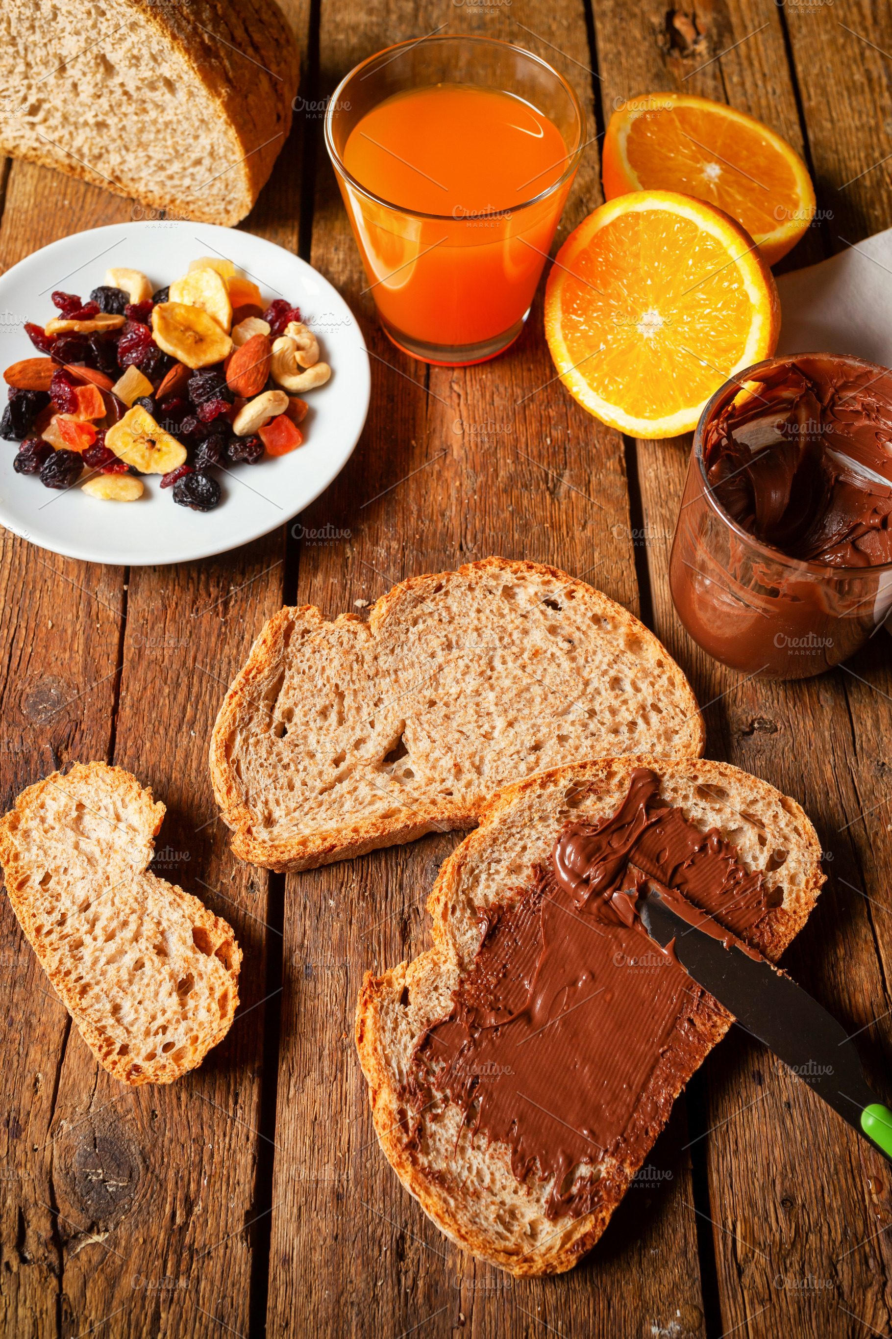 Spreading chocolate cream on whole wheat bread for breakfast with orange juice, a Food & Drink Photo by Antonio Gravante Market