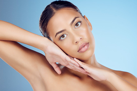 Portrait, woman and cosmetic hands on studio blue background for skincare salon, body makeup and beauty. Young model, face and natural glow of aesthetic wellness spa, healthy shine or facial collagen, a Photo by Peopleimages.com