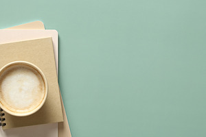 Banner with cup of coffee, stack of paper notebooks and eucalyptus leaves on gr