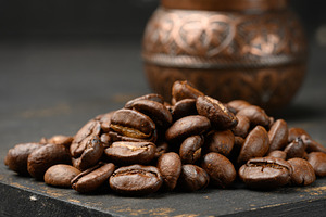 A handful of roasted coffee beans, dark wooden surface, a Food & Drink Photo by ndanko